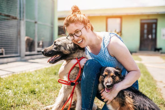 A woman hugs two dogs