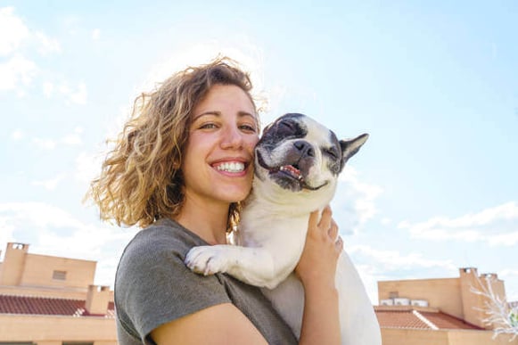 A smiling woman holds a dog outside