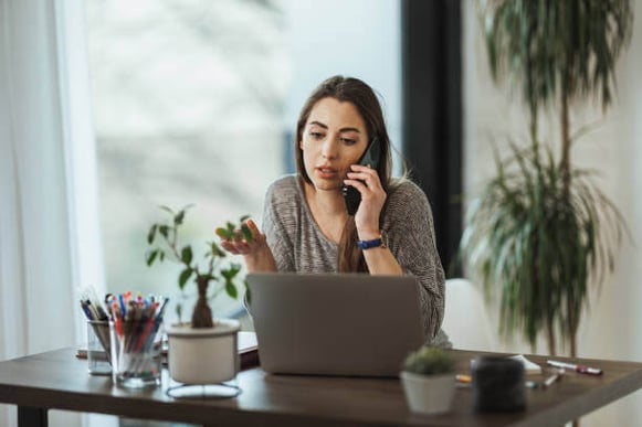 A woman talks on a phone with a serious expression