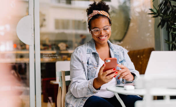 A woman holds her cell phone and smiles at it