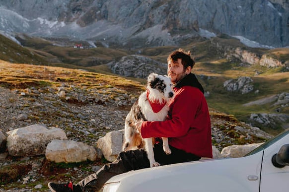 A man holds his dog while adventuring outdoors