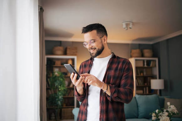 A man looks down at his cell phone while inside