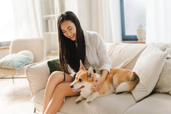 A woman and dog sit on a couch together