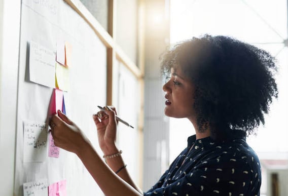 A woman looks at sticky notes on a board